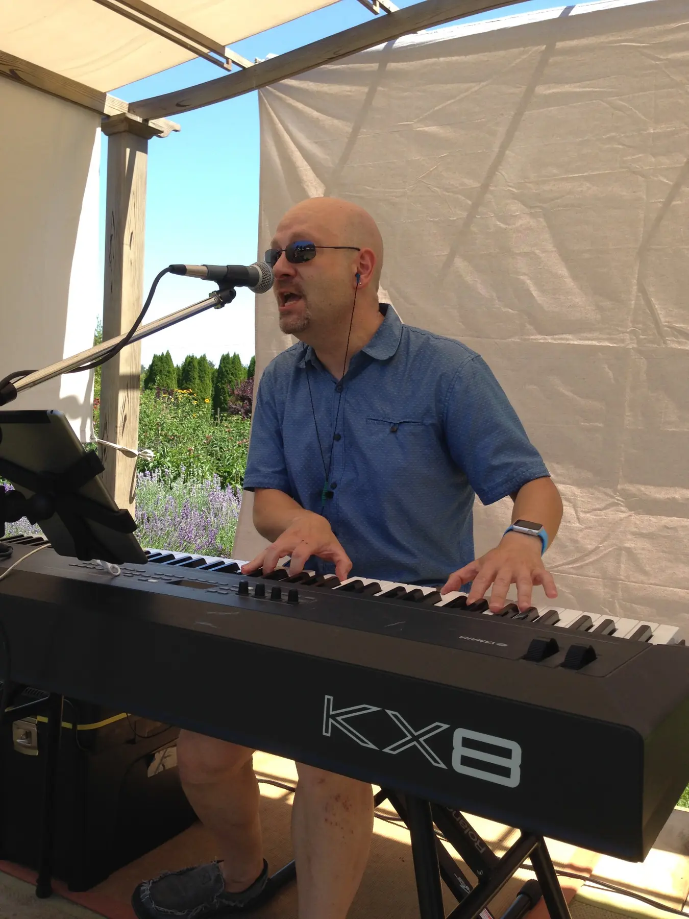 Paul singing while playing keyboard at an outdoor event